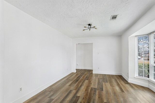 spare room with dark hardwood / wood-style floors and a textured ceiling