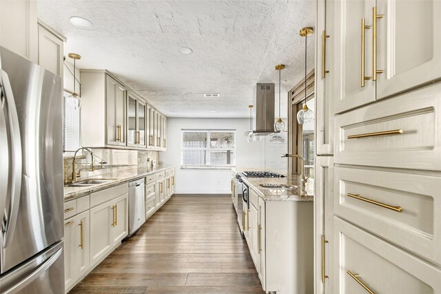 kitchen with stainless steel appliances, light stone countertops, sink, and decorative light fixtures