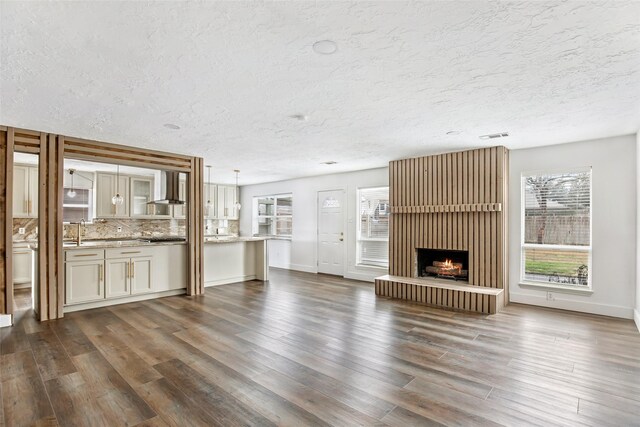 unfurnished living room with a brick fireplace, dark hardwood / wood-style floors, and a textured ceiling