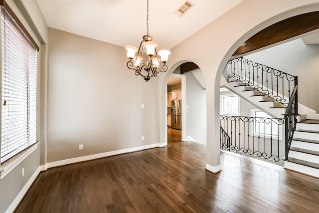 unfurnished dining area with dark wood-type flooring and a notable chandelier