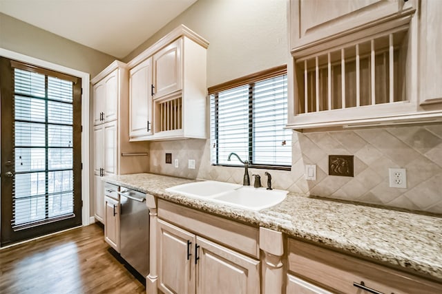 kitchen featuring light brown cabinetry, sink, stainless steel dishwasher, hardwood / wood-style floors, and decorative backsplash