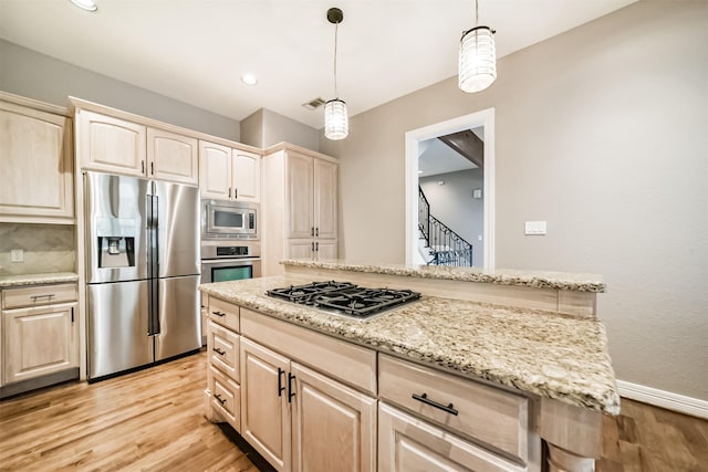 kitchen with pendant lighting, light hardwood / wood-style flooring, appliances with stainless steel finishes, light stone counters, and light brown cabinetry