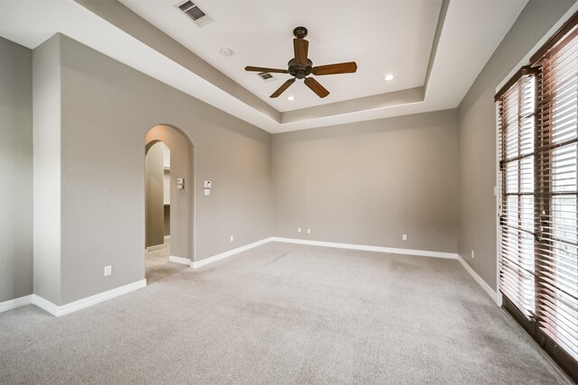 carpeted spare room featuring ceiling fan and a tray ceiling