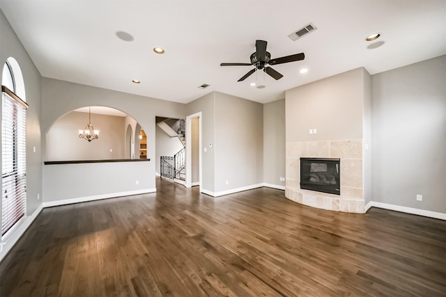 unfurnished living room with dark wood-type flooring, a fireplace, and ceiling fan with notable chandelier