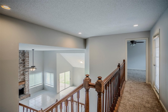 hall featuring vaulted ceiling, a textured ceiling, and light tile patterned floors