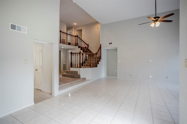 tiled spare room featuring a towering ceiling and ceiling fan