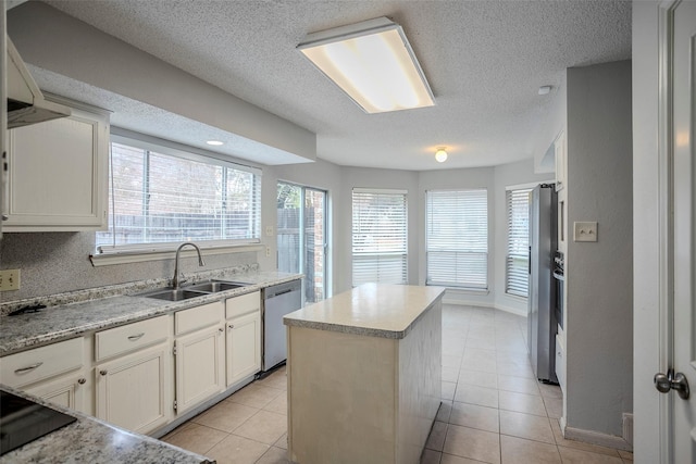 kitchen with stainless steel appliances, sink, a kitchen island, and light tile patterned floors