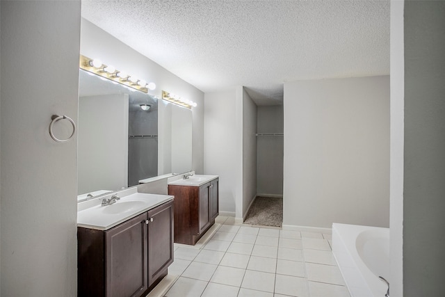 bathroom featuring vanity, tile patterned flooring, a washtub, and a textured ceiling