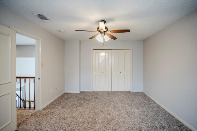 unfurnished bedroom with ceiling fan, a closet, carpet, and a textured ceiling