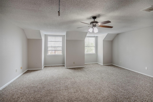 additional living space with lofted ceiling, carpet flooring, a textured ceiling, and ceiling fan