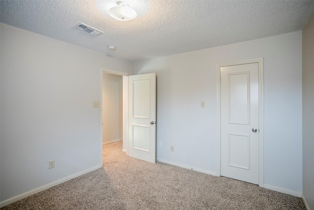 unfurnished room featuring carpet and a textured ceiling