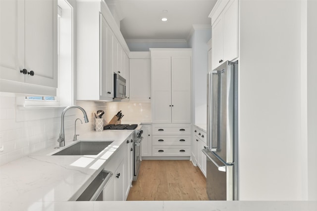 kitchen featuring sink, premium appliances, light stone countertops, white cabinets, and decorative backsplash