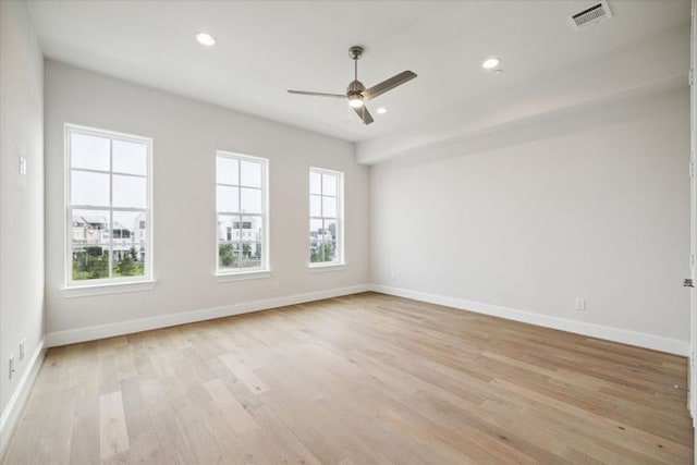 empty room with plenty of natural light, ceiling fan, and light hardwood / wood-style flooring