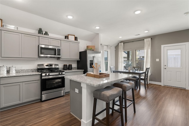 kitchen with gray cabinetry, light stone counters, a center island, and appliances with stainless steel finishes