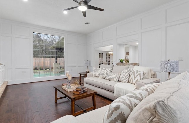 living room featuring dark hardwood / wood-style flooring, crown molding, and ceiling fan