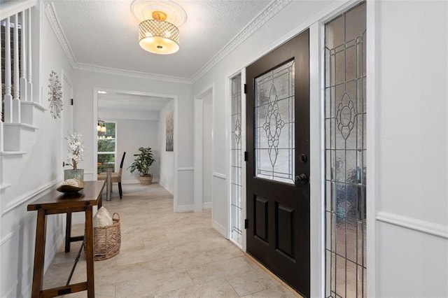 entrance foyer with ornamental molding and a textured ceiling