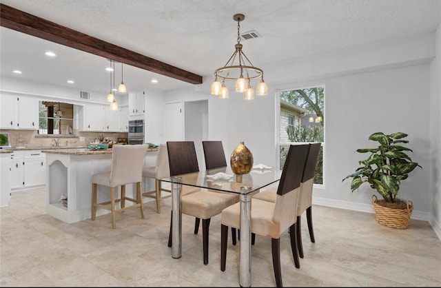 dining room with a chandelier, a textured ceiling, and beam ceiling