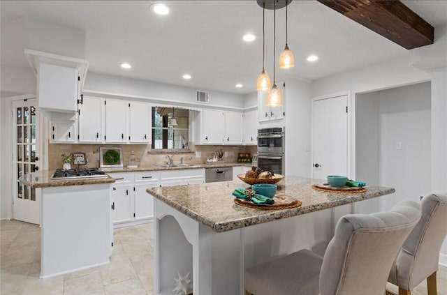 kitchen with stainless steel appliances, white cabinetry, a center island, and light stone counters