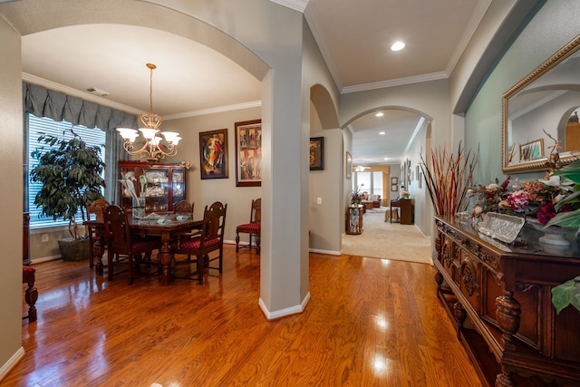 dining room with wood-type flooring, ornamental molding, and a chandelier