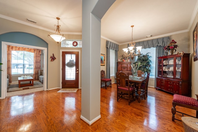 entryway featuring hardwood / wood-style flooring, crown molding, and a notable chandelier