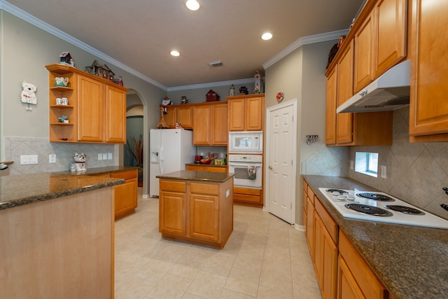 kitchen with ornamental molding, a center island, dark stone countertops, and white appliances