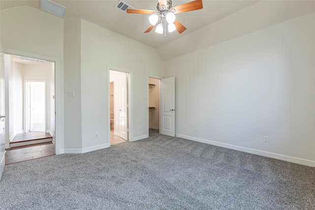 unfurnished bedroom with lofted ceiling, connected bathroom, a walk in closet, ceiling fan, and carpet