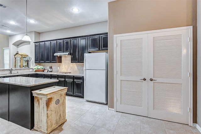 kitchen featuring pendant lighting, sink, white refrigerator, tasteful backsplash, and stainless steel gas cooktop