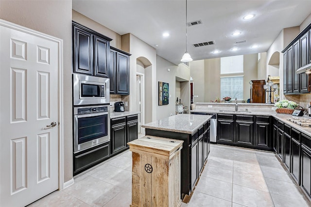 kitchen featuring sink, kitchen peninsula, a kitchen island, stainless steel appliances, and backsplash