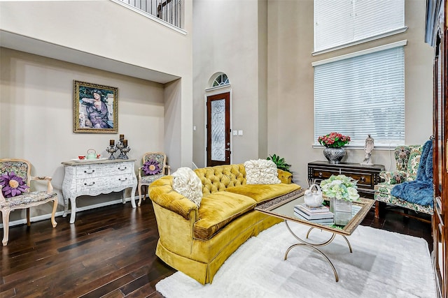 living room with dark wood-type flooring and a towering ceiling