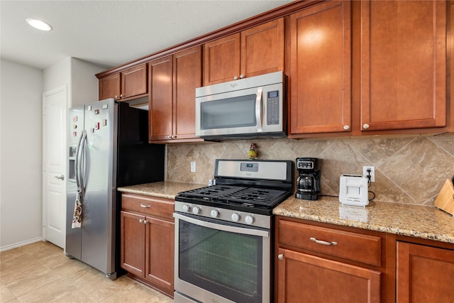 kitchen featuring tasteful backsplash, light stone countertops, and appliances with stainless steel finishes