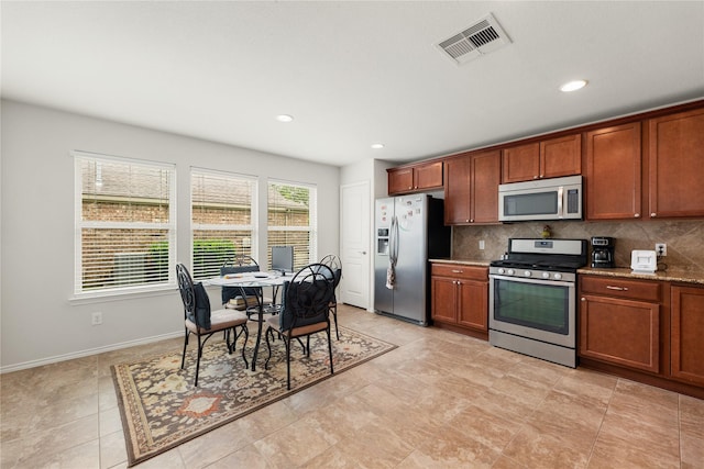 kitchen featuring light stone countertops, appliances with stainless steel finishes, and decorative backsplash