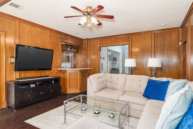 living room with bar area, dark hardwood / wood-style floors, ceiling fan, and wood walls