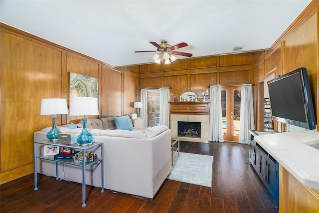 living room featuring ceiling fan, dark hardwood / wood-style flooring, and wood walls