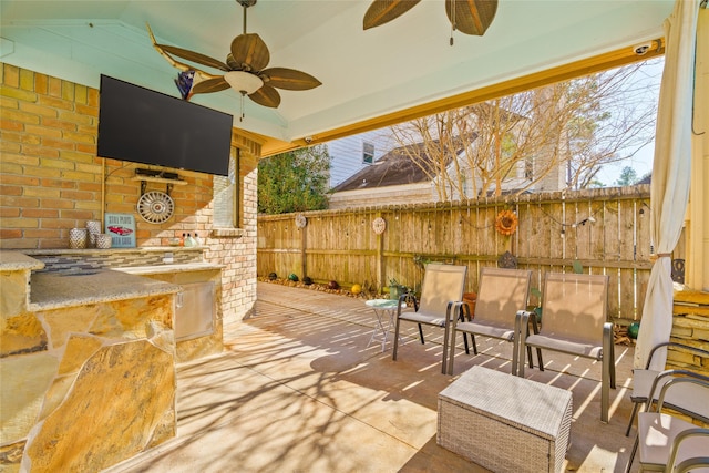 view of patio with ceiling fan and an outdoor bar