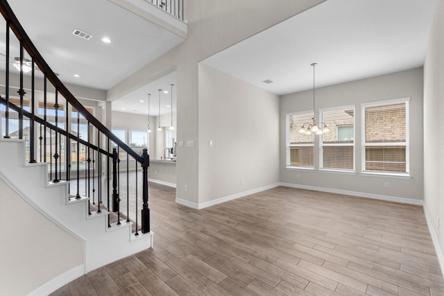 foyer entrance featuring wood-type flooring and a chandelier