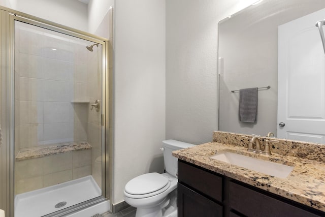 bathroom with vanity, a shower with door, and toilet