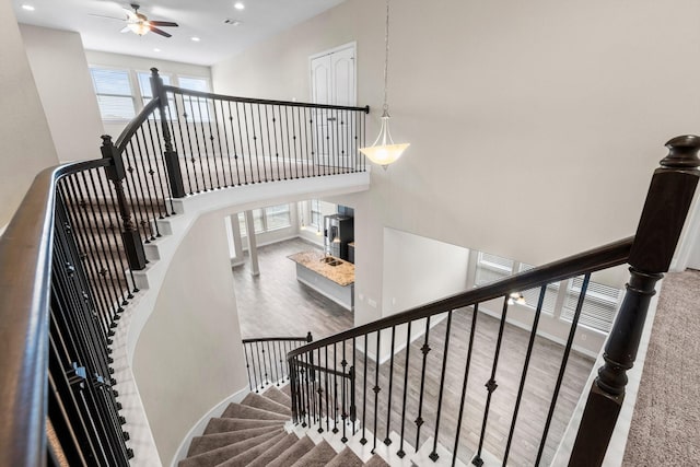 stairs with a high ceiling, hardwood / wood-style floors, and ceiling fan