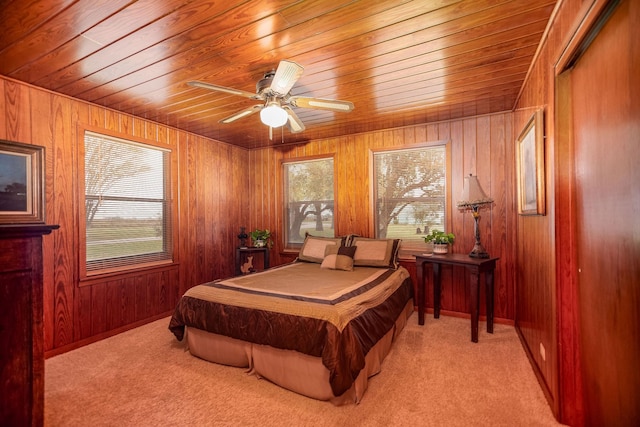 carpeted bedroom with ceiling fan, wooden ceiling, and wooden walls