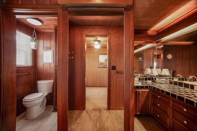 bathroom with vanity, wood-type flooring, toilet, and wood walls