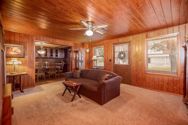 living room with wooden walls, wooden ceiling, ceiling fan, and carpet flooring