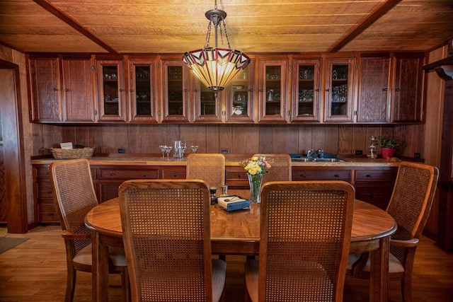 dining area featuring sink, hardwood / wood-style floors, wood ceiling, and wood walls