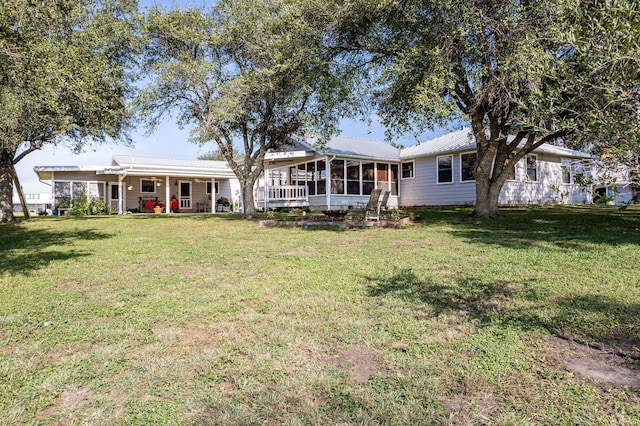 rear view of house featuring a sunroom and a lawn