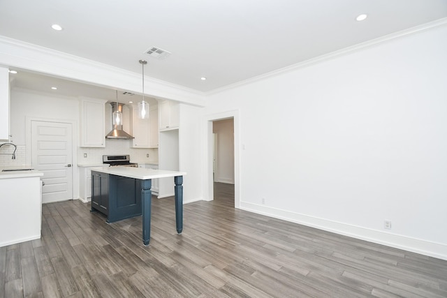 kitchen with wall chimney range hood, hanging light fixtures, white cabinets, a kitchen bar, and stainless steel range with electric cooktop