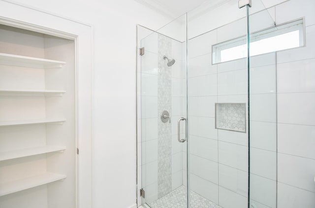 bathroom with a shower with door and ornamental molding