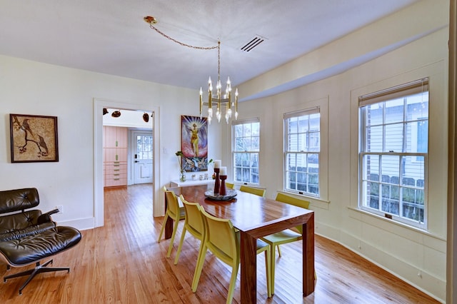 dining room featuring a notable chandelier, light hardwood / wood-style flooring, and a healthy amount of sunlight