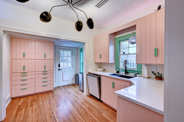 kitchen featuring sink, light hardwood / wood-style flooring, dishwasher, pendant lighting, and light stone countertops