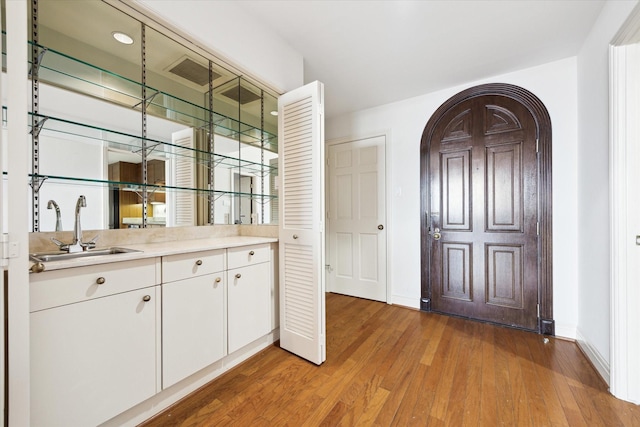 bar with hardwood / wood-style flooring, sink, and white cabinets