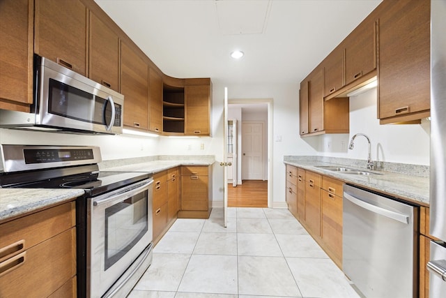 kitchen with light stone countertops, appliances with stainless steel finishes, sink, and light tile patterned floors