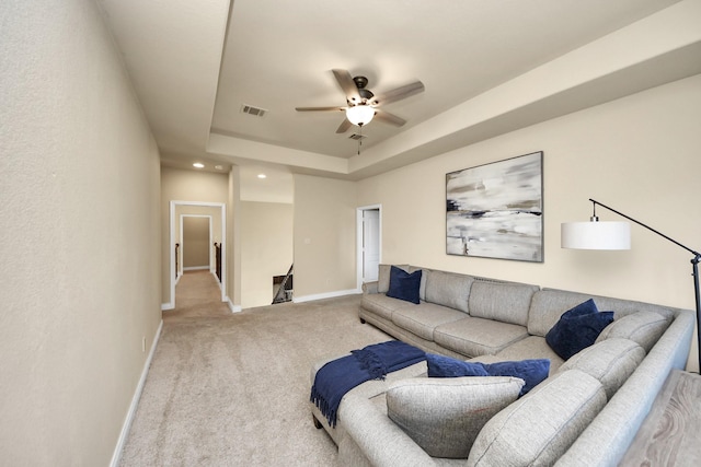 carpeted living room featuring ceiling fan and a tray ceiling