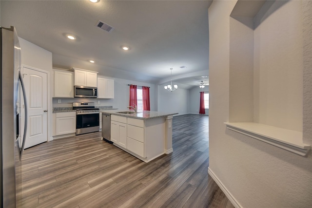 kitchen with a kitchen island, pendant lighting, white cabinetry, light stone counters, and stainless steel appliances